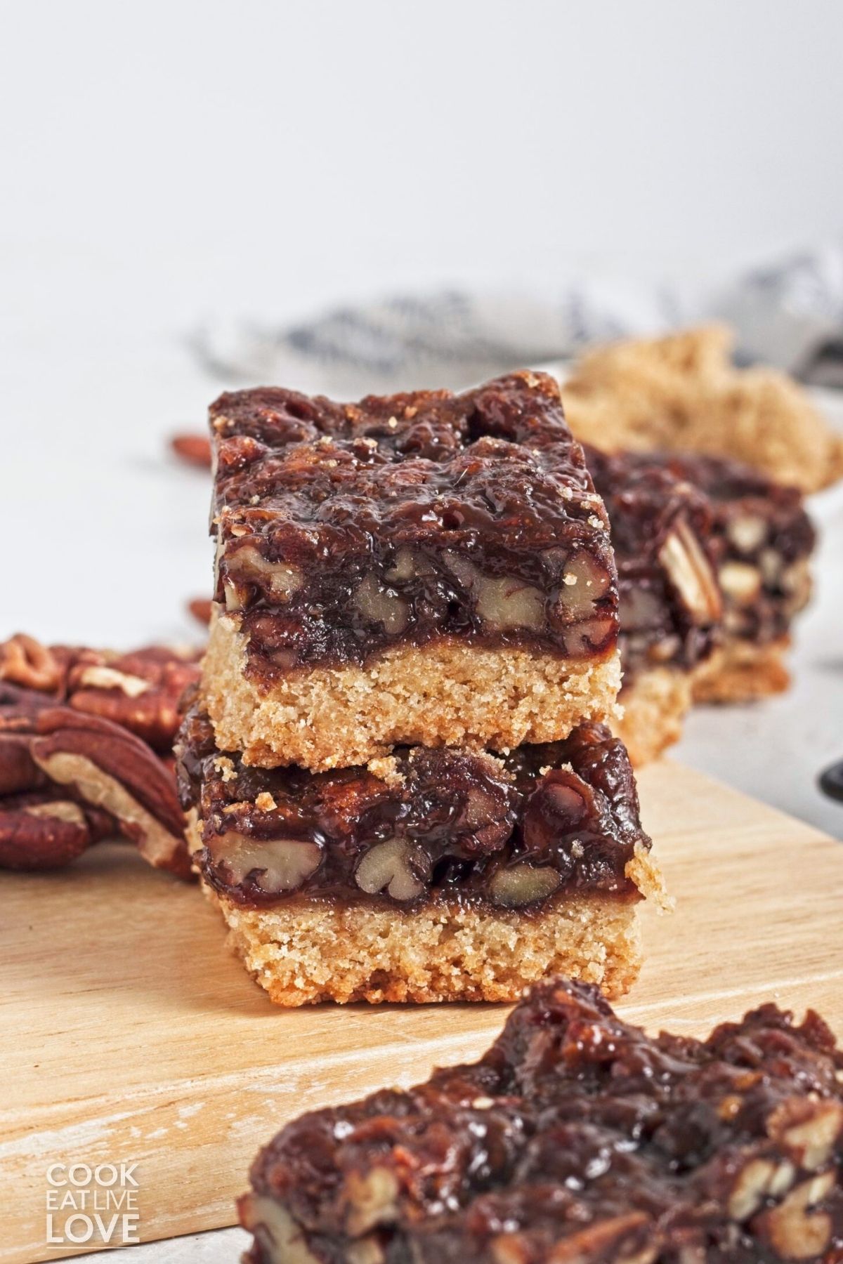 Two vegan pecan pie bars stacked on top with more in the background.