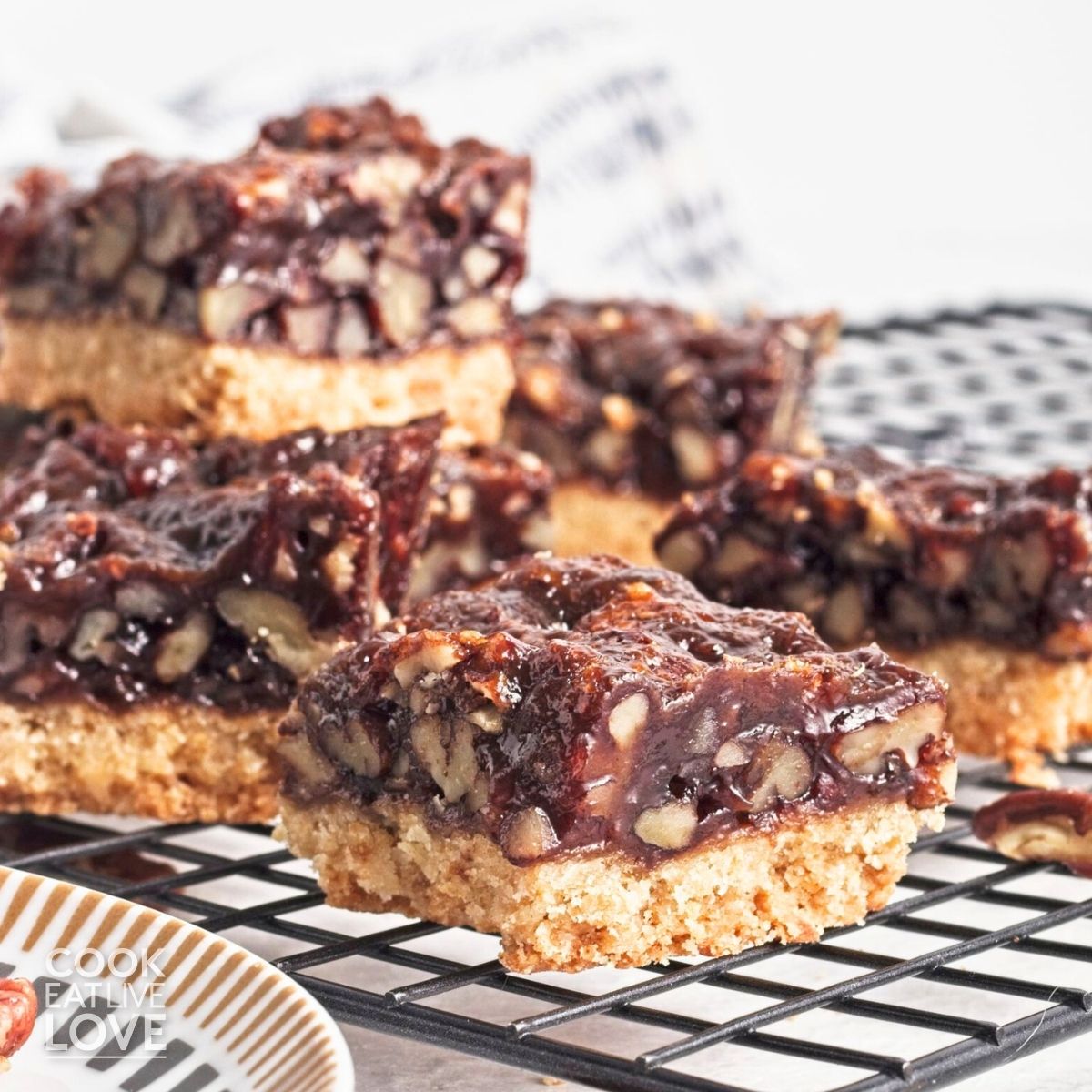 Vegan pecan bars piled up on a wire baking rack.