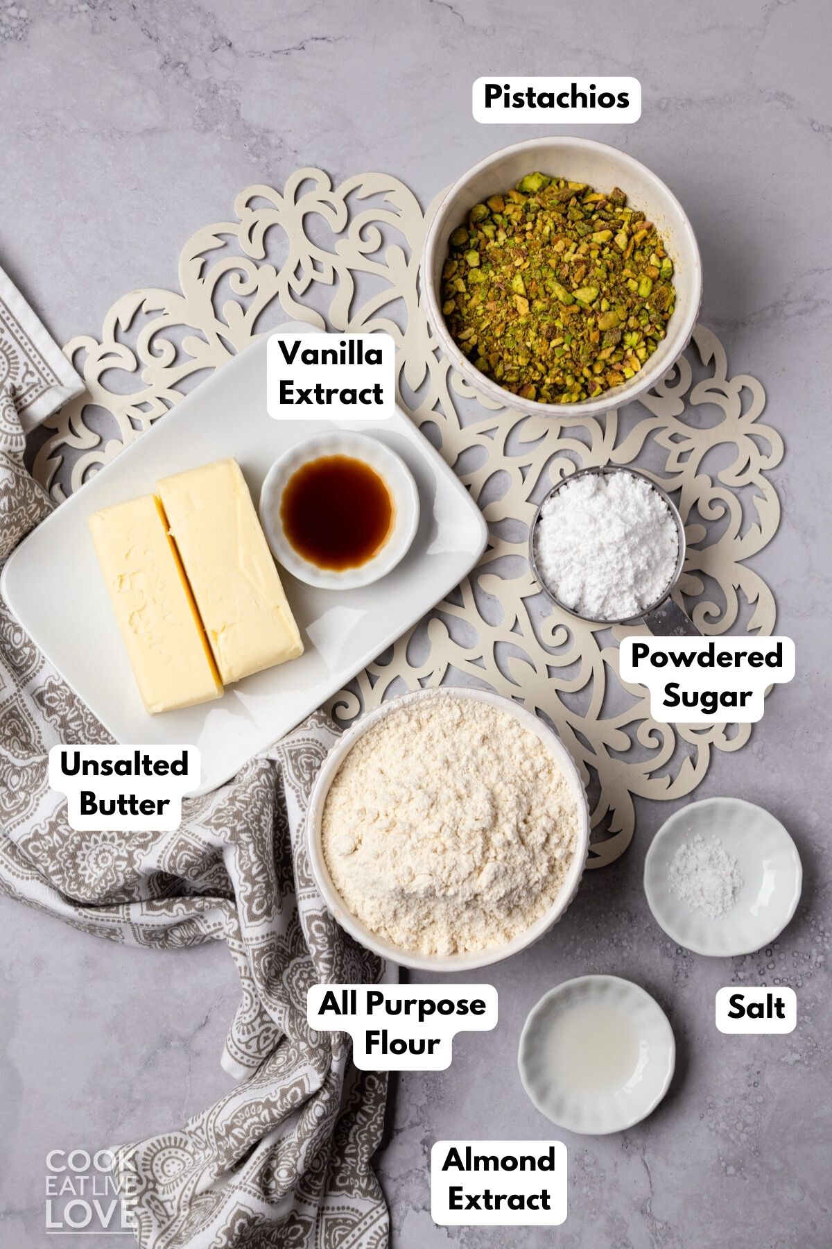 Ingredients to make pistachio snowball cookies in bowls with labels. 