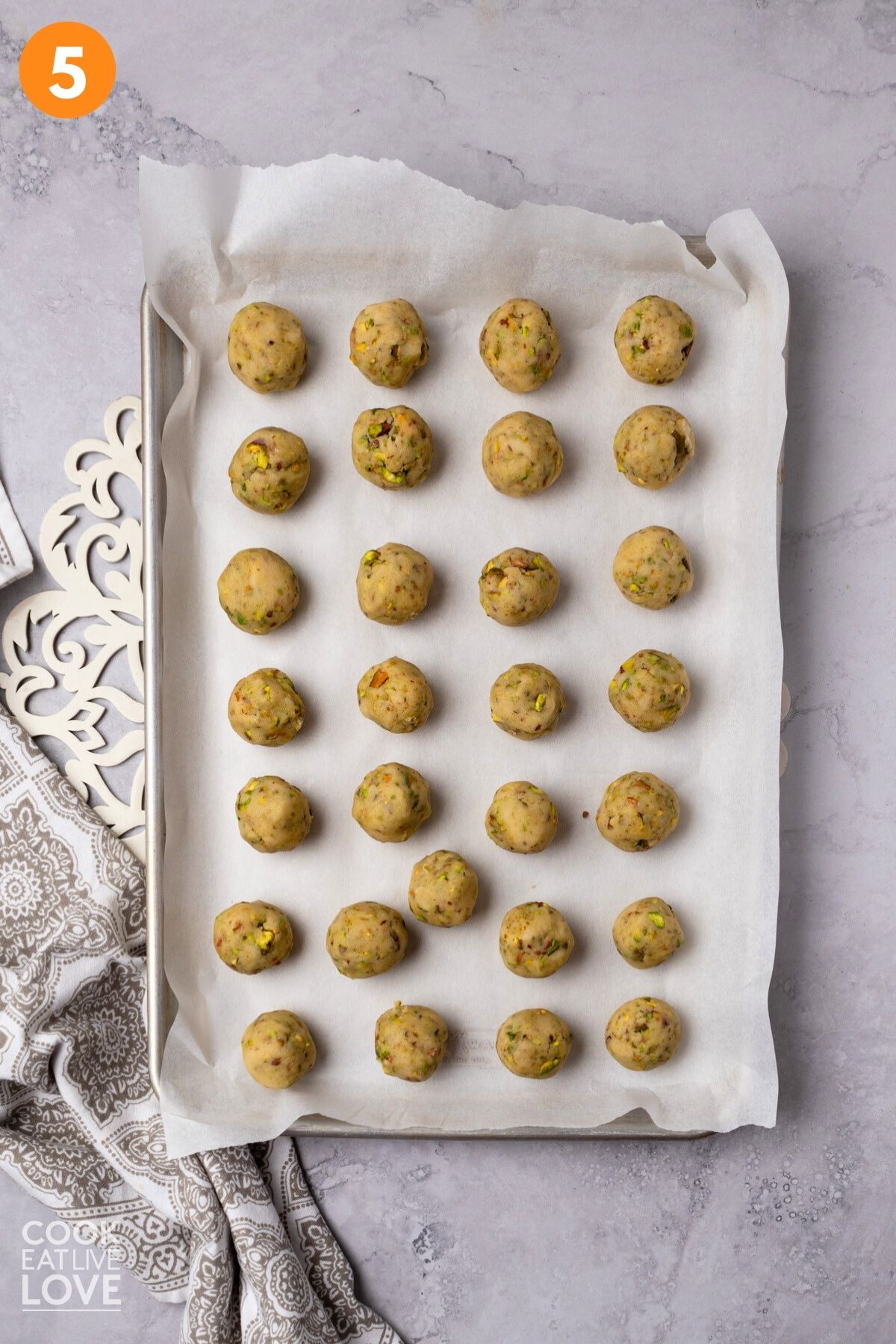 Pistachio cookie dough shaped into balls on a baking tray.