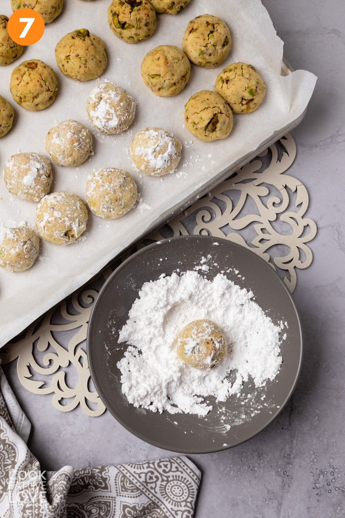 Rolling the baked cookies in powdered sugar. 