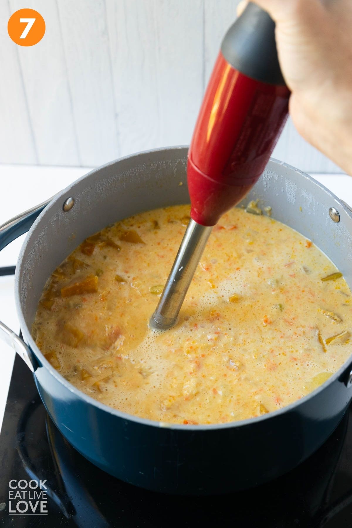 A stick blender in the pot of soup.