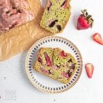 A slice of matcha banana bread with strawberries on a plate.