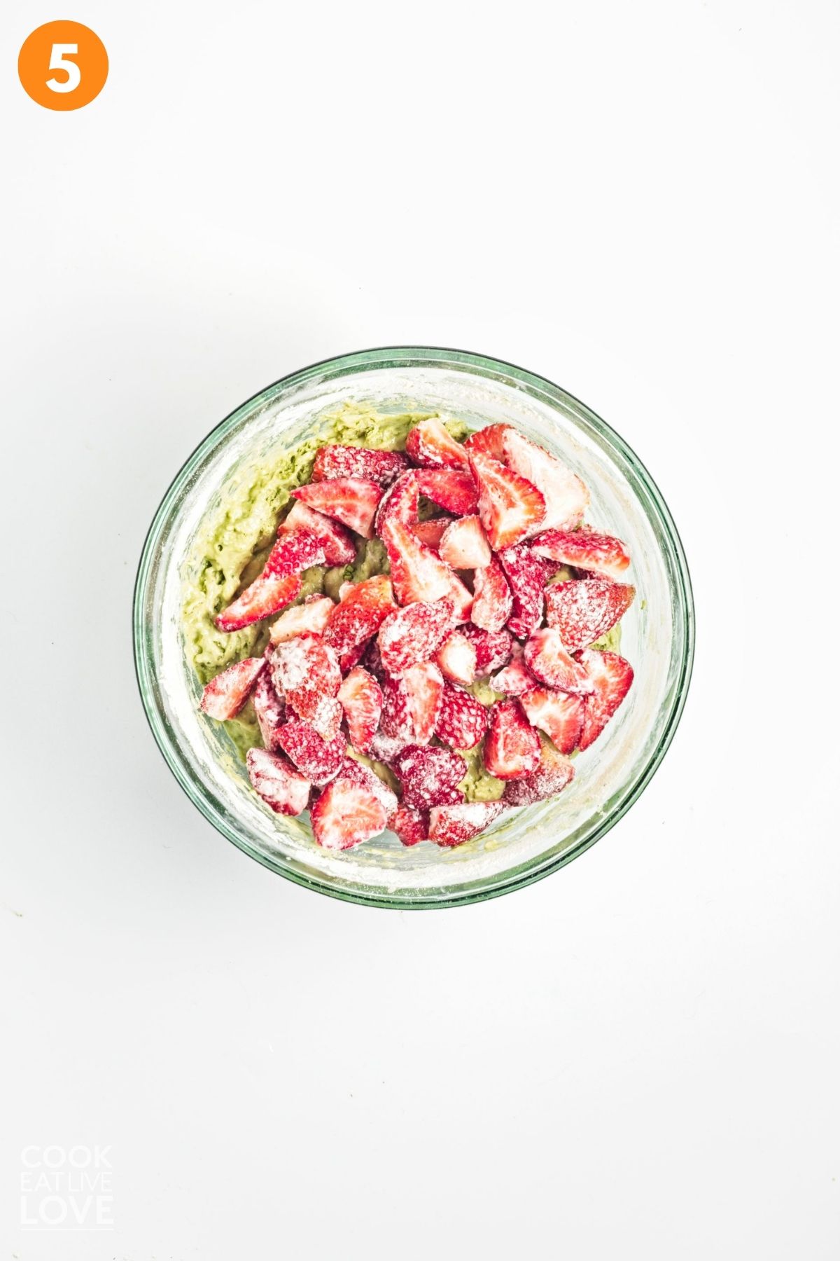 Flour dusted strawberries added to the bowl of matcha banana bread batter. 