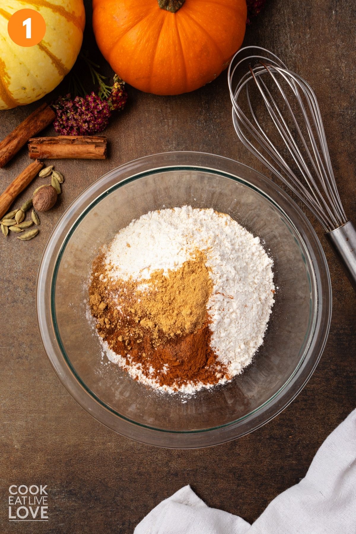 Flour, baking powder, salt, and spices added to a mixing bowl. 