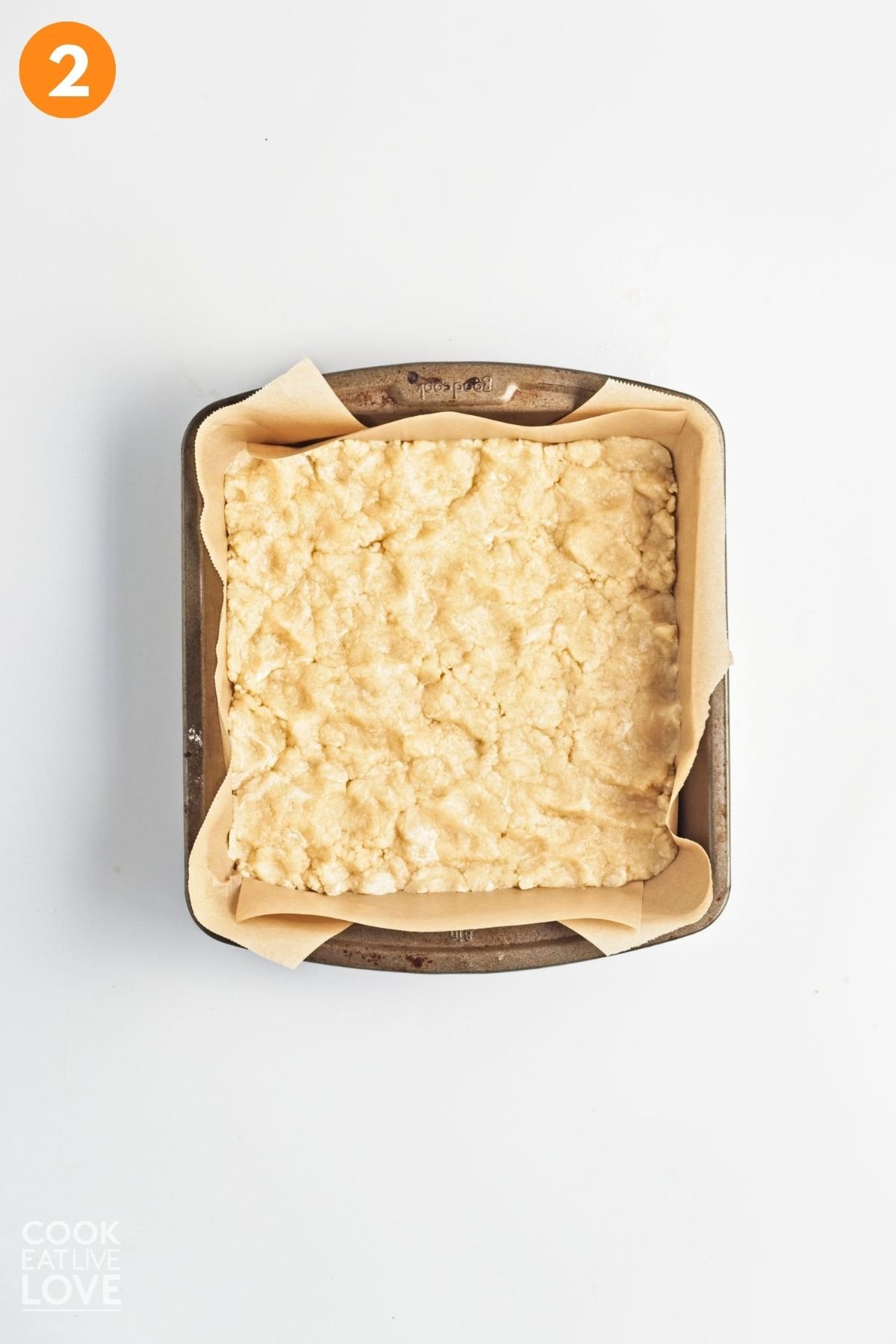 Crust pressed into a square pan with parchment paper. 