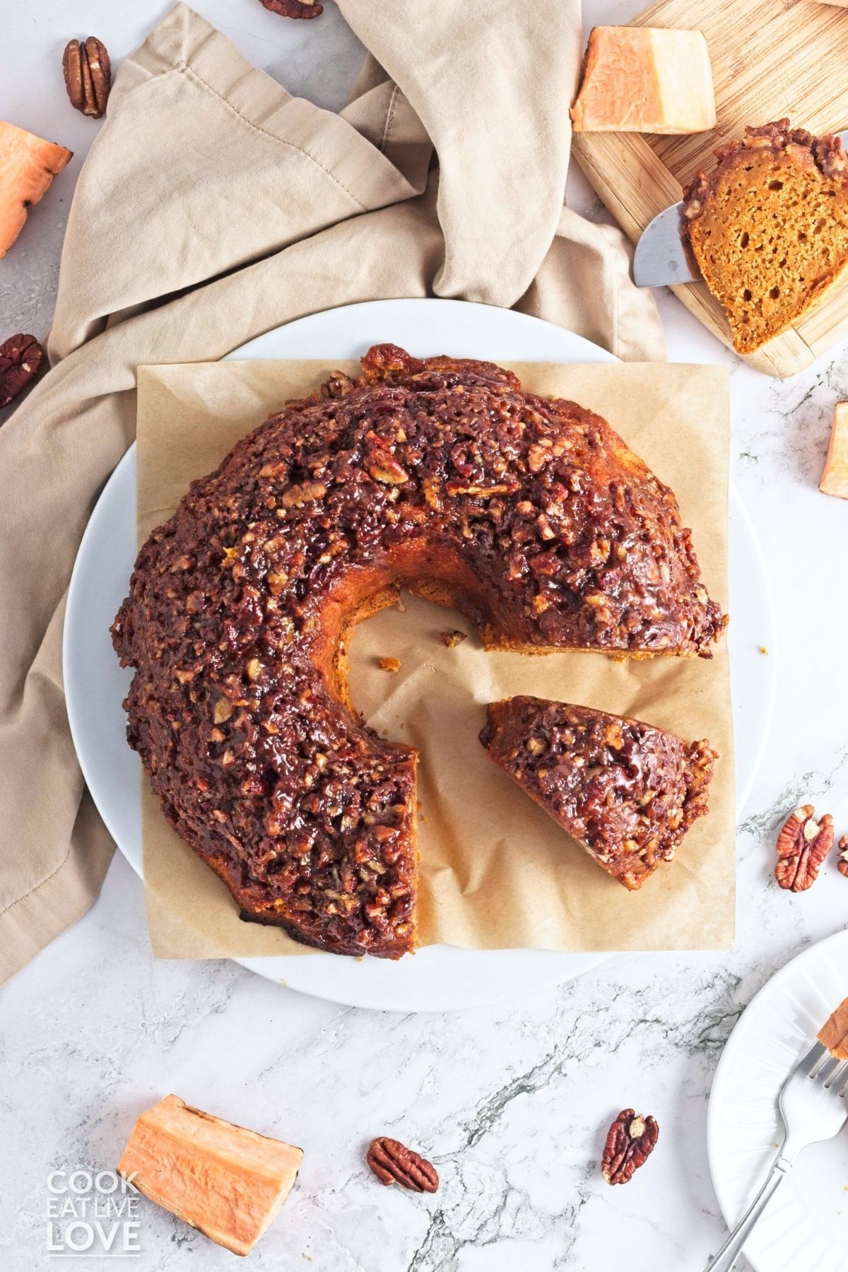 A sweet potato bundt cake on a piece of parchment with a slices missing and one sitting to the side.