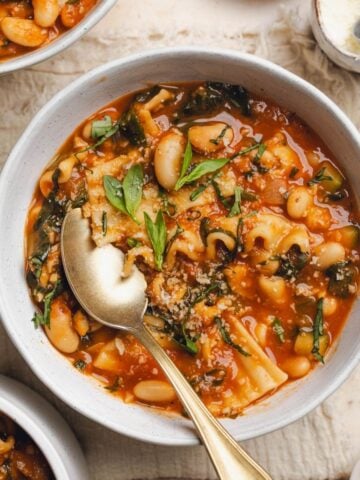A bowl of vegan lasagna soup with a spoon resting in the bowl.