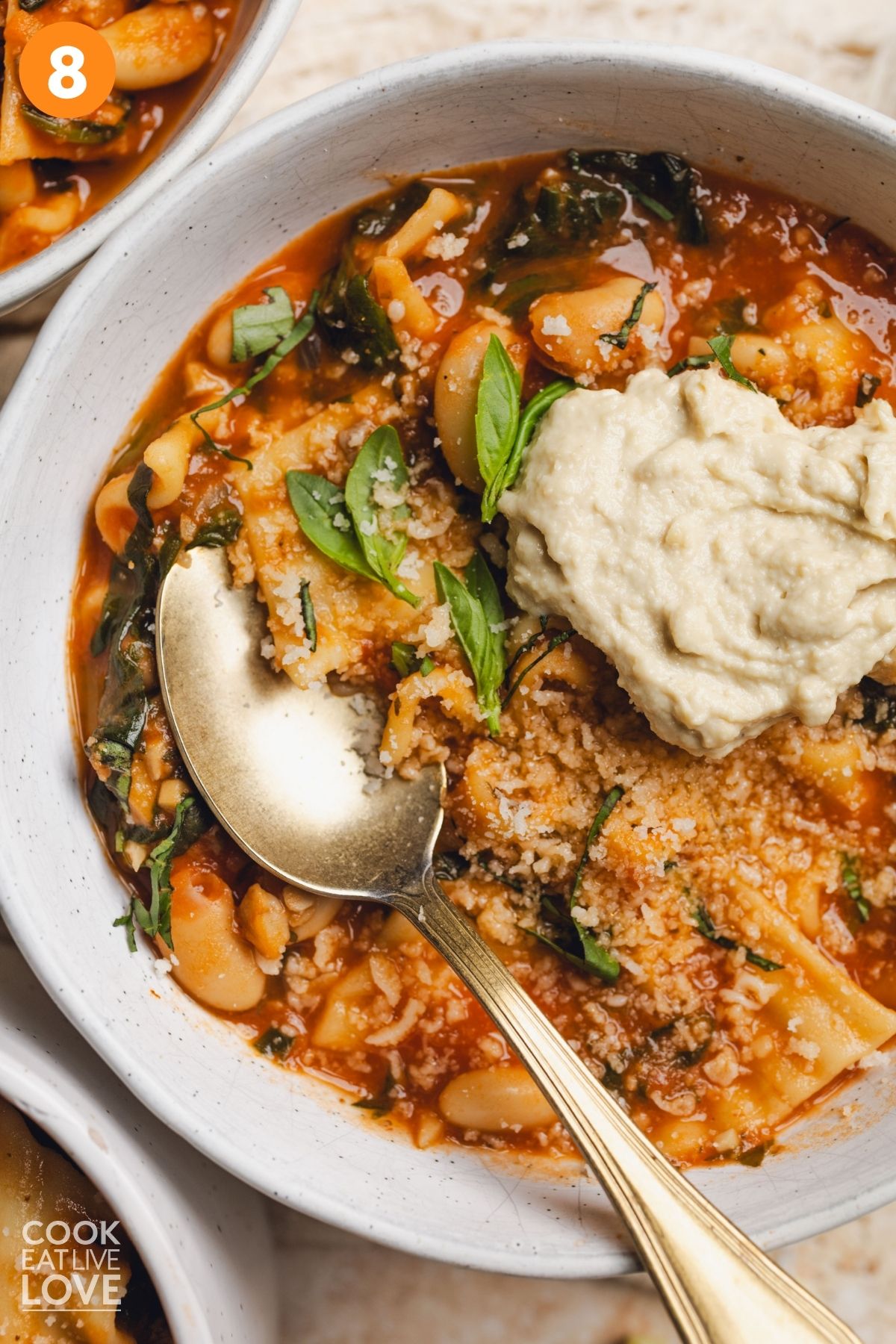 A bowl of vegan lasagna soup with a dollop of vegan ricotta on top.