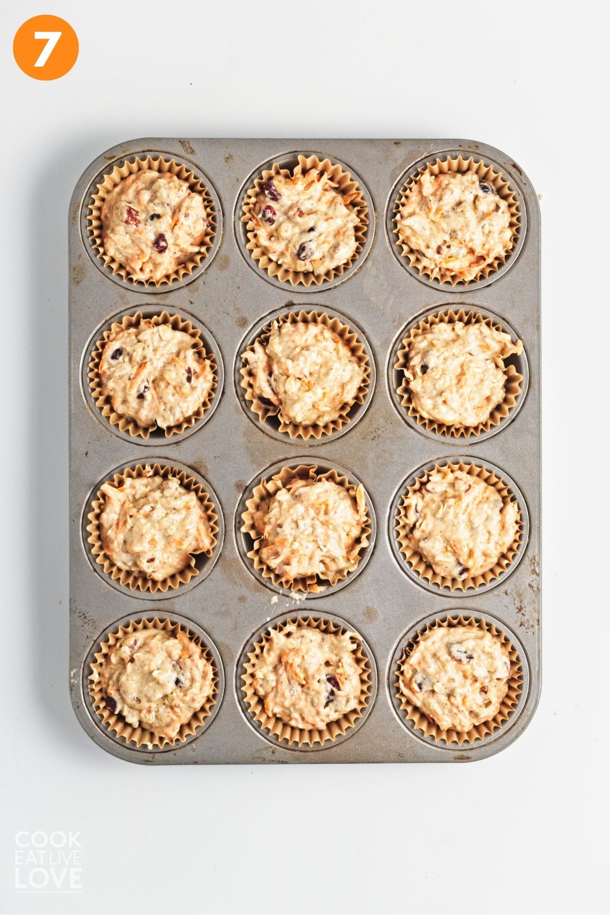 Carrot cake muffin batter added to a muffin pan.