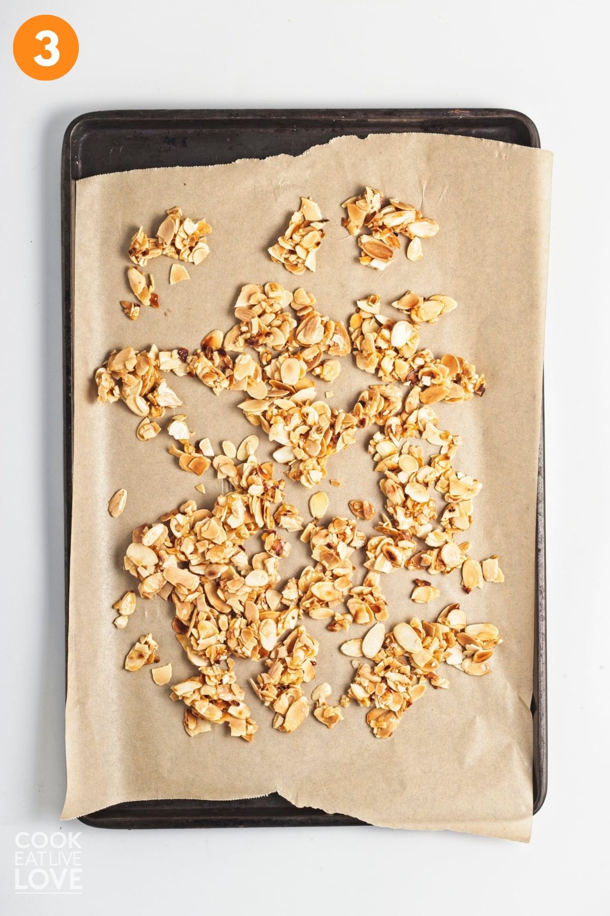 Sugared almonds spread out on a baking tray. 