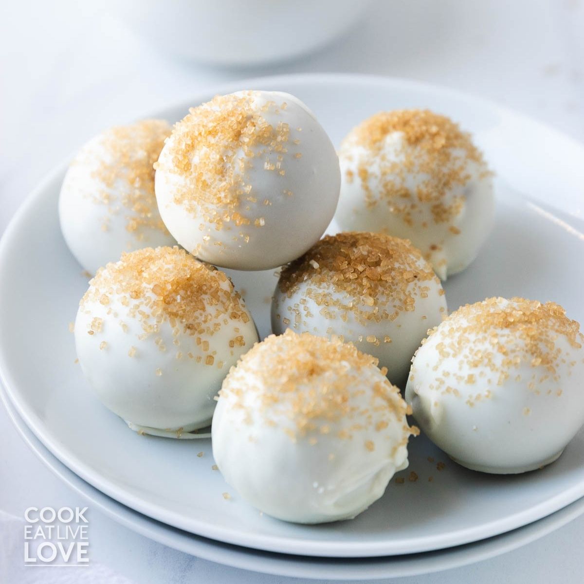 Gingerbread truffles on a plate coated in white chocolate and sprinkled with sugar.