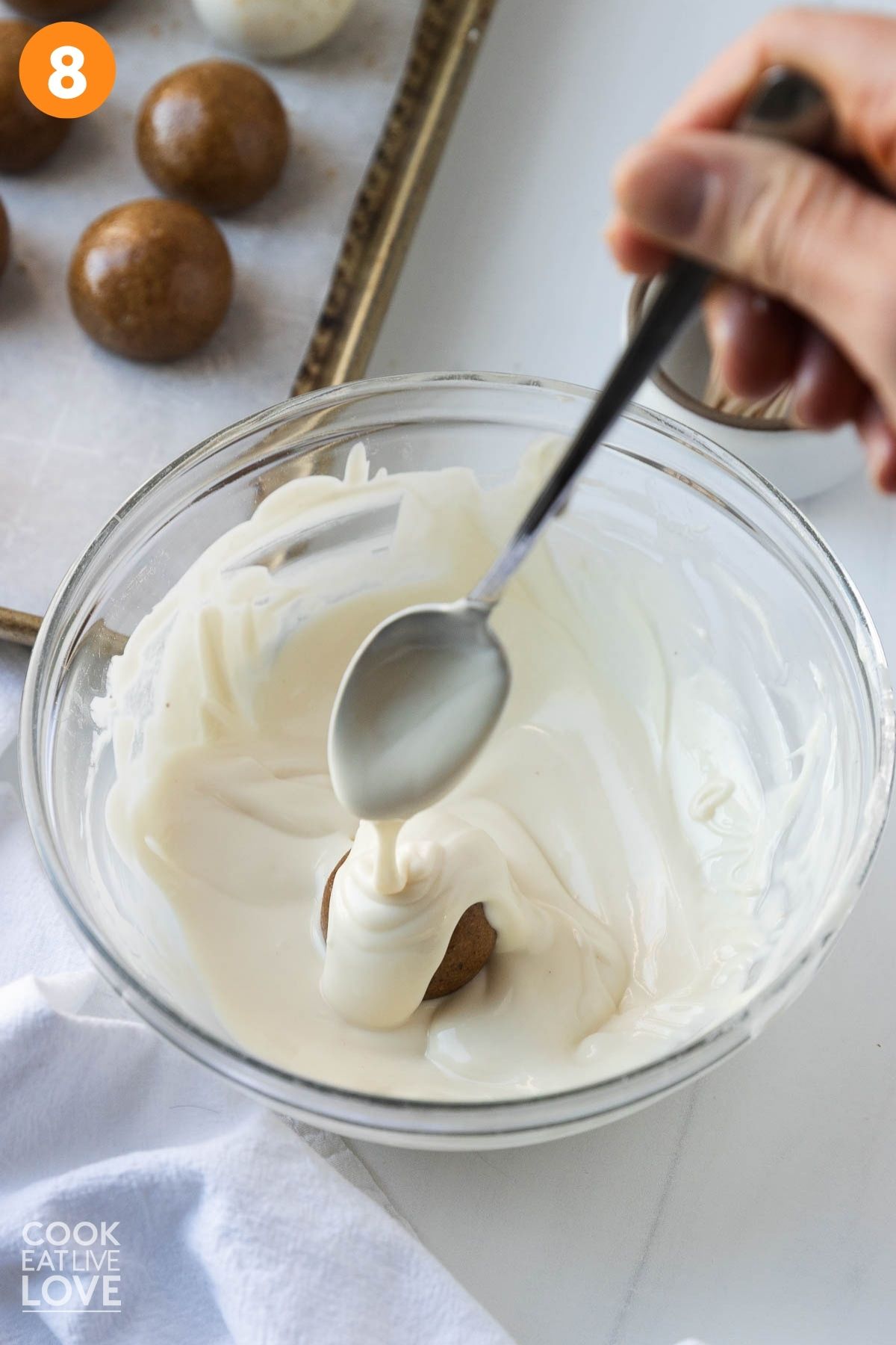 A spoon dipping the balls into the melted chocolate.