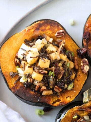 Vegetarian stuffed acorn squash filled with wild rice on a plate.