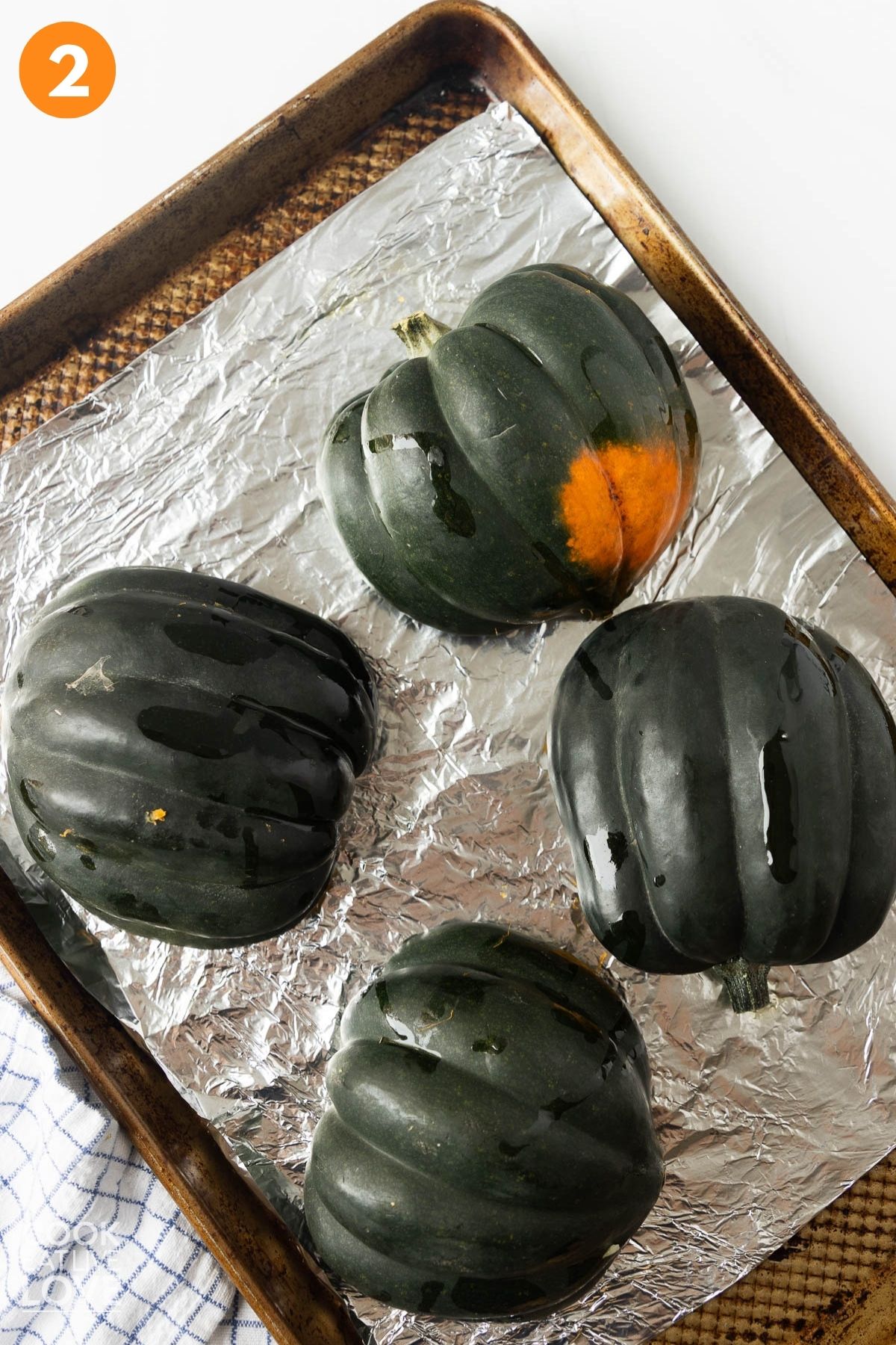 Acorn squash turned over face down on a baking pan.