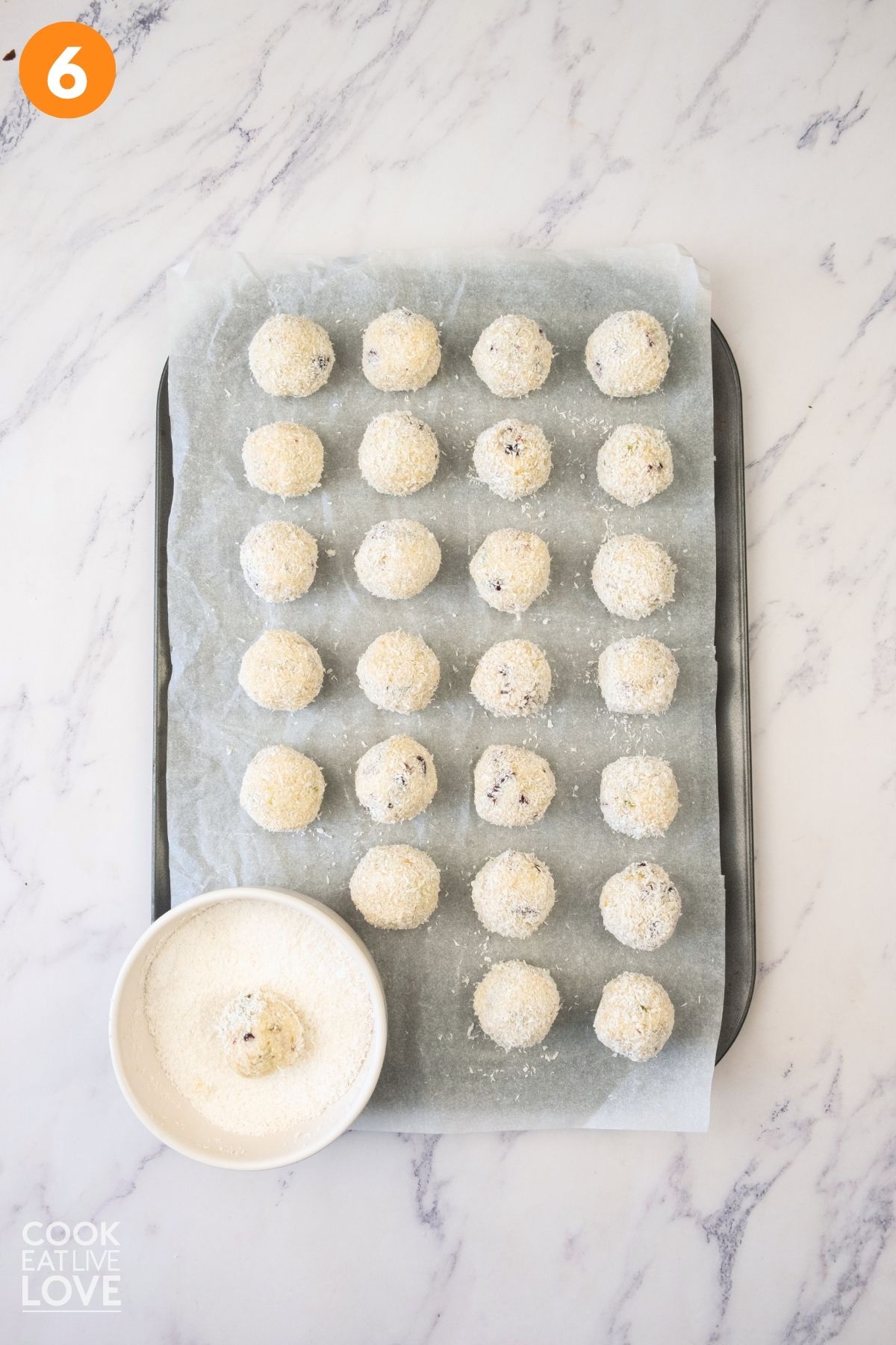 White chocolate truffles rolled into balls and coconut on a baking tray. 