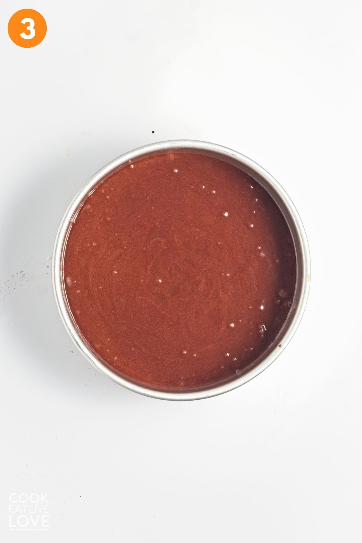 Chocolate cake batter added into a lined pan.