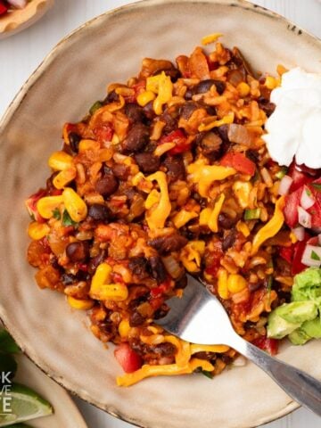Taco rice in a bowl topped with sour cream and avocado.