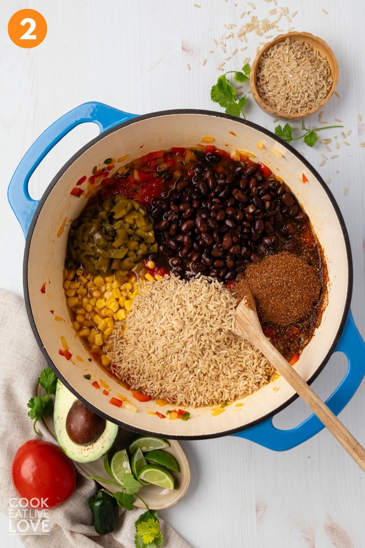 Beans, tomatoes, green chilies, brown rice, taco seasoning, and vegetable broth added to the skillet.
