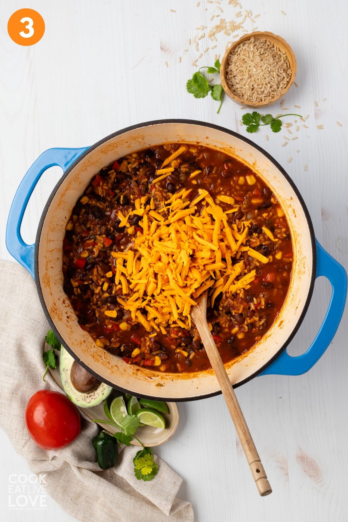 The rice mixture boiling in the skillet with cheese on top.