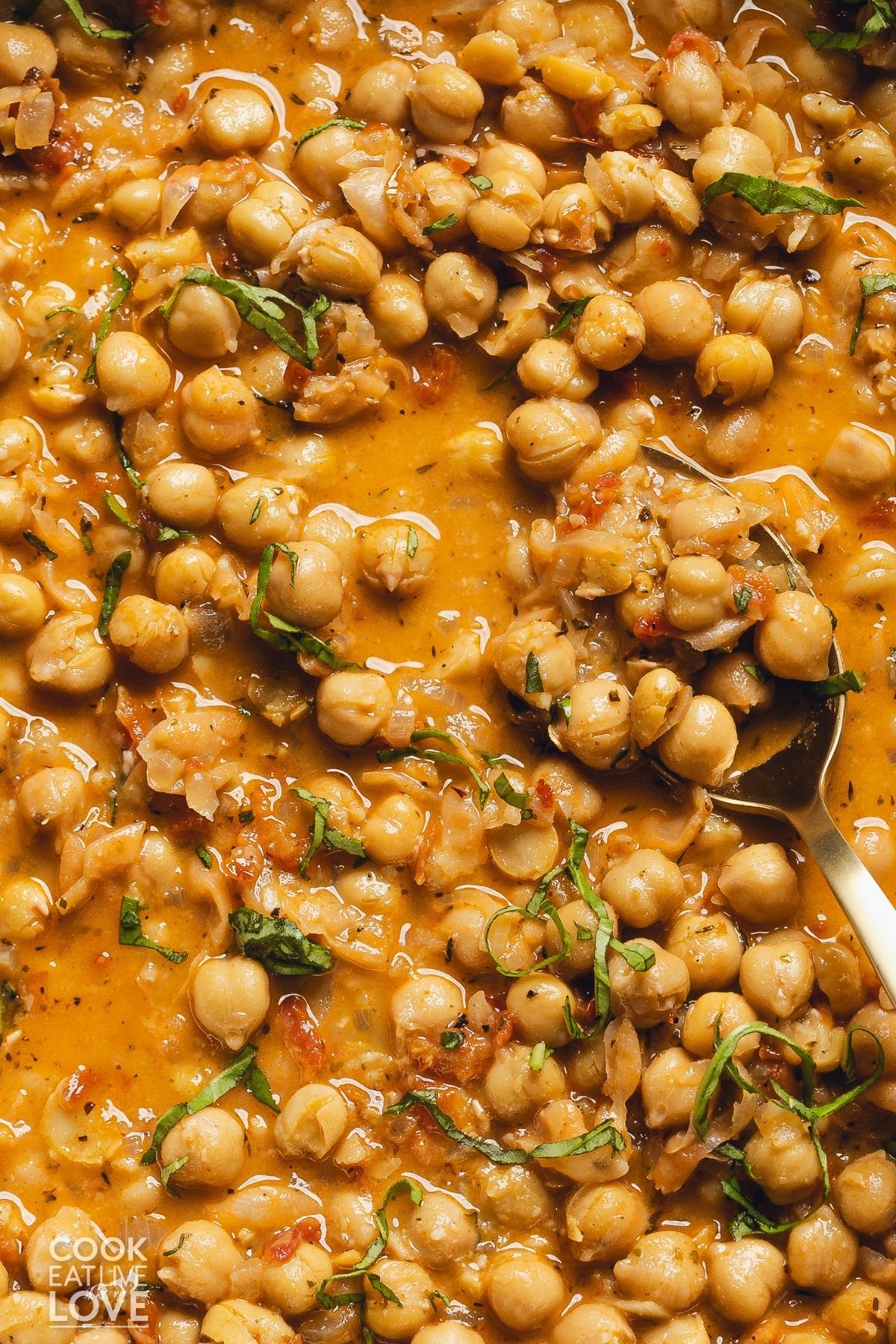 A spoon scooping out some Marry me chickpeas in a sauce.