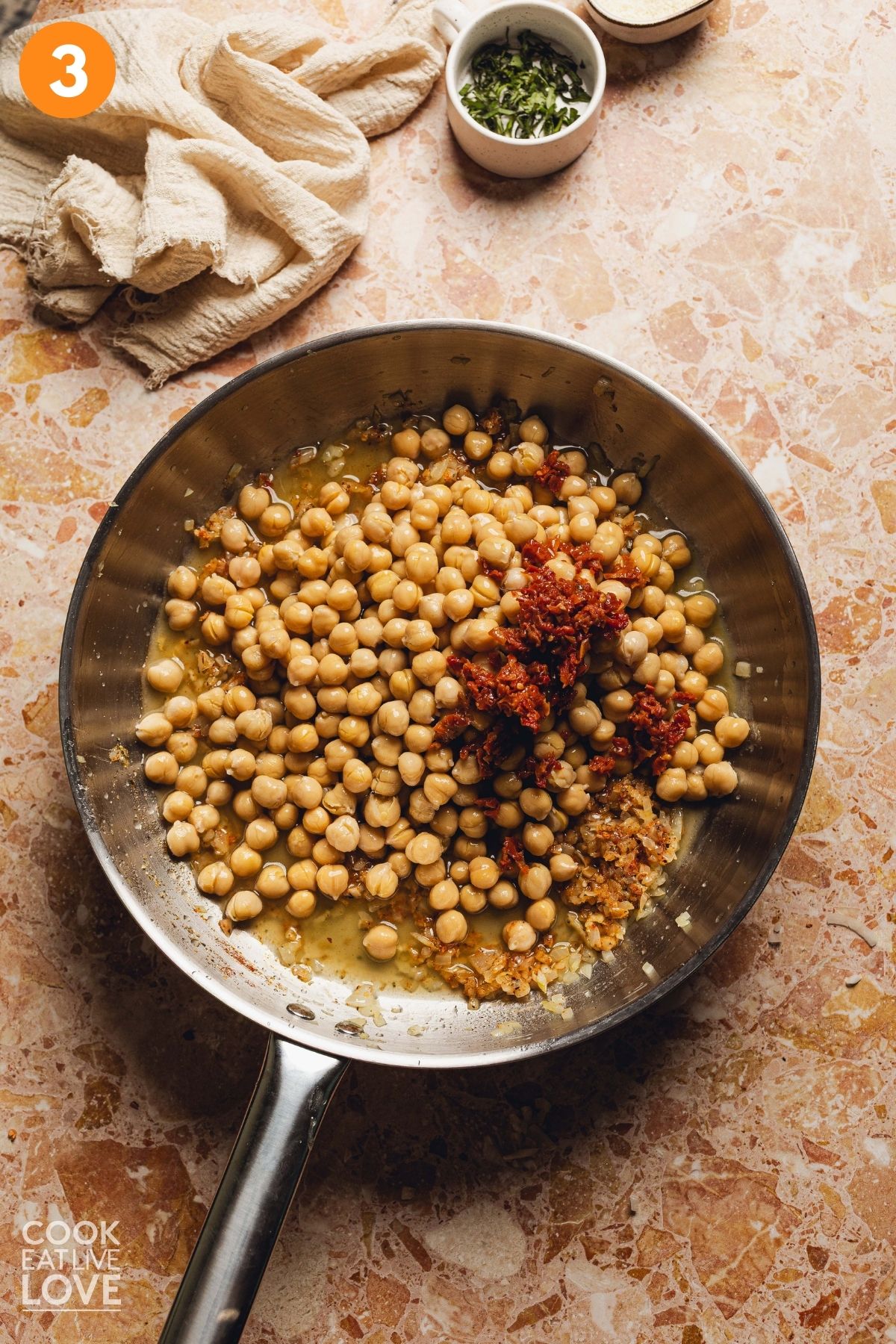 Chickpeas, sundried tomatoes, and vegetable broth added to the skillet.