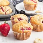 Strawberry banana muffins with fresh strawberries and banana slices around them.