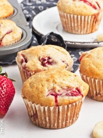 Strawberry banana muffins with fresh strawberries and banana slices around them.