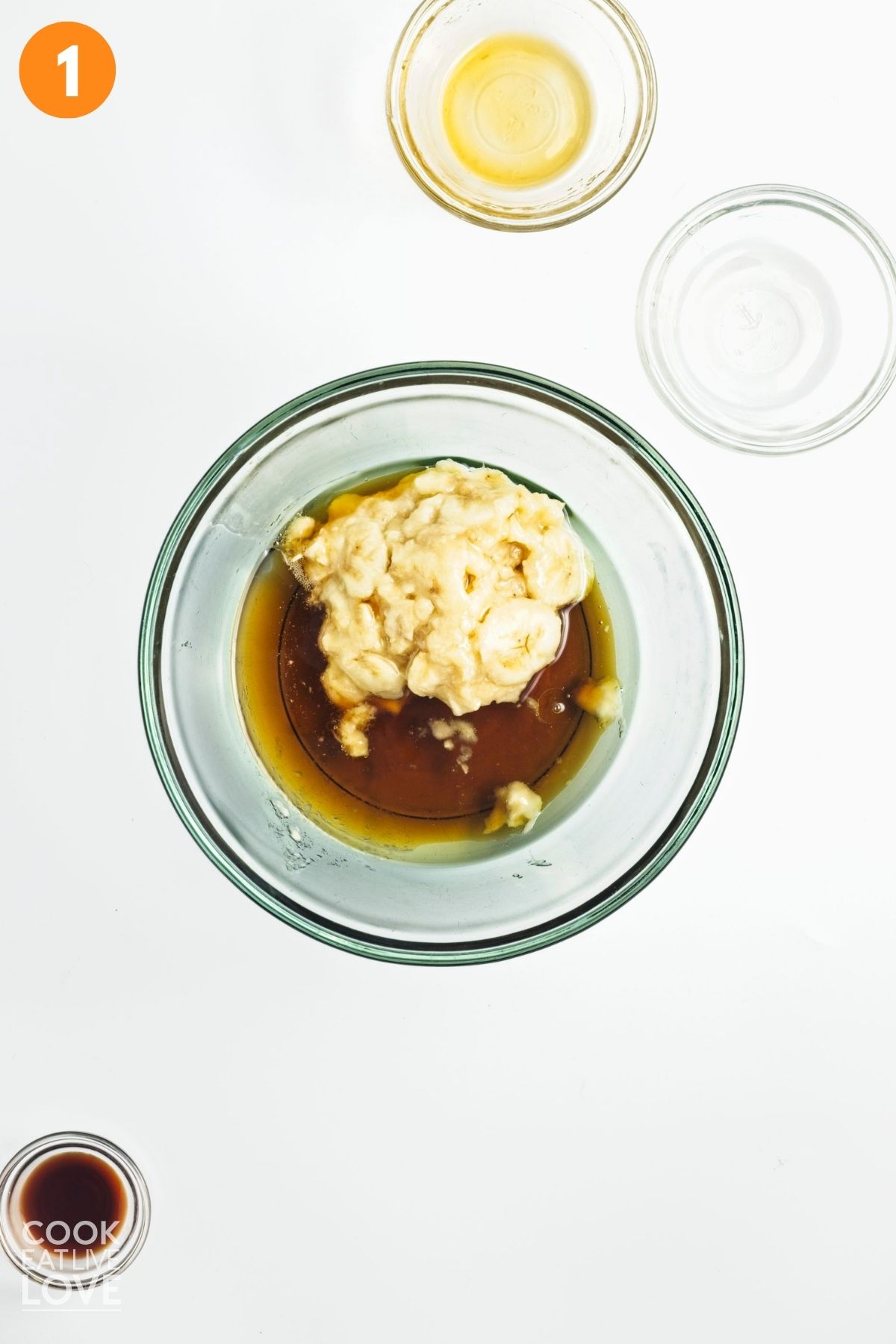 Maple syrup, mashed bananas and oil in a bowl.