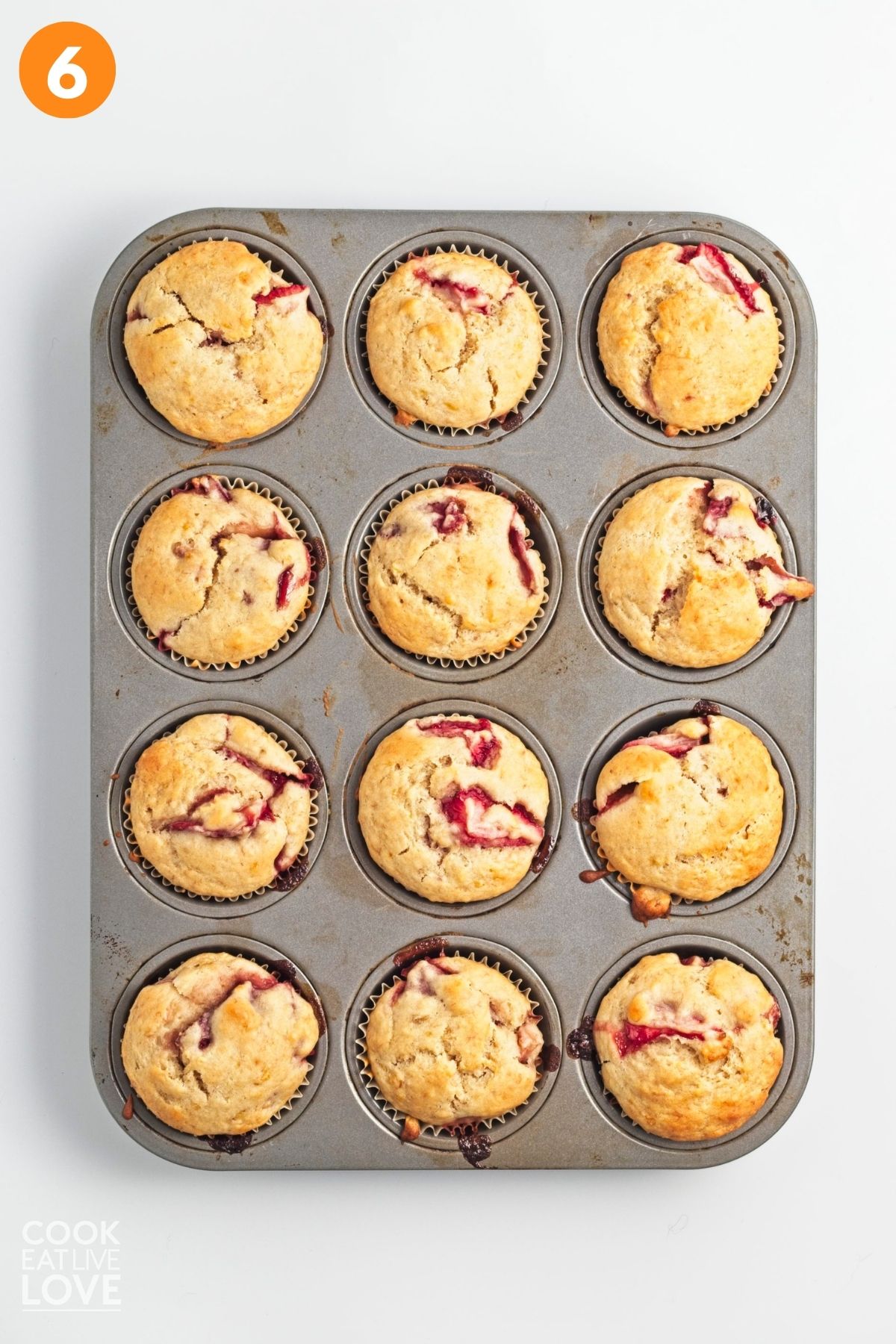 A muffin tin filled with baked banana strawberry muffins.