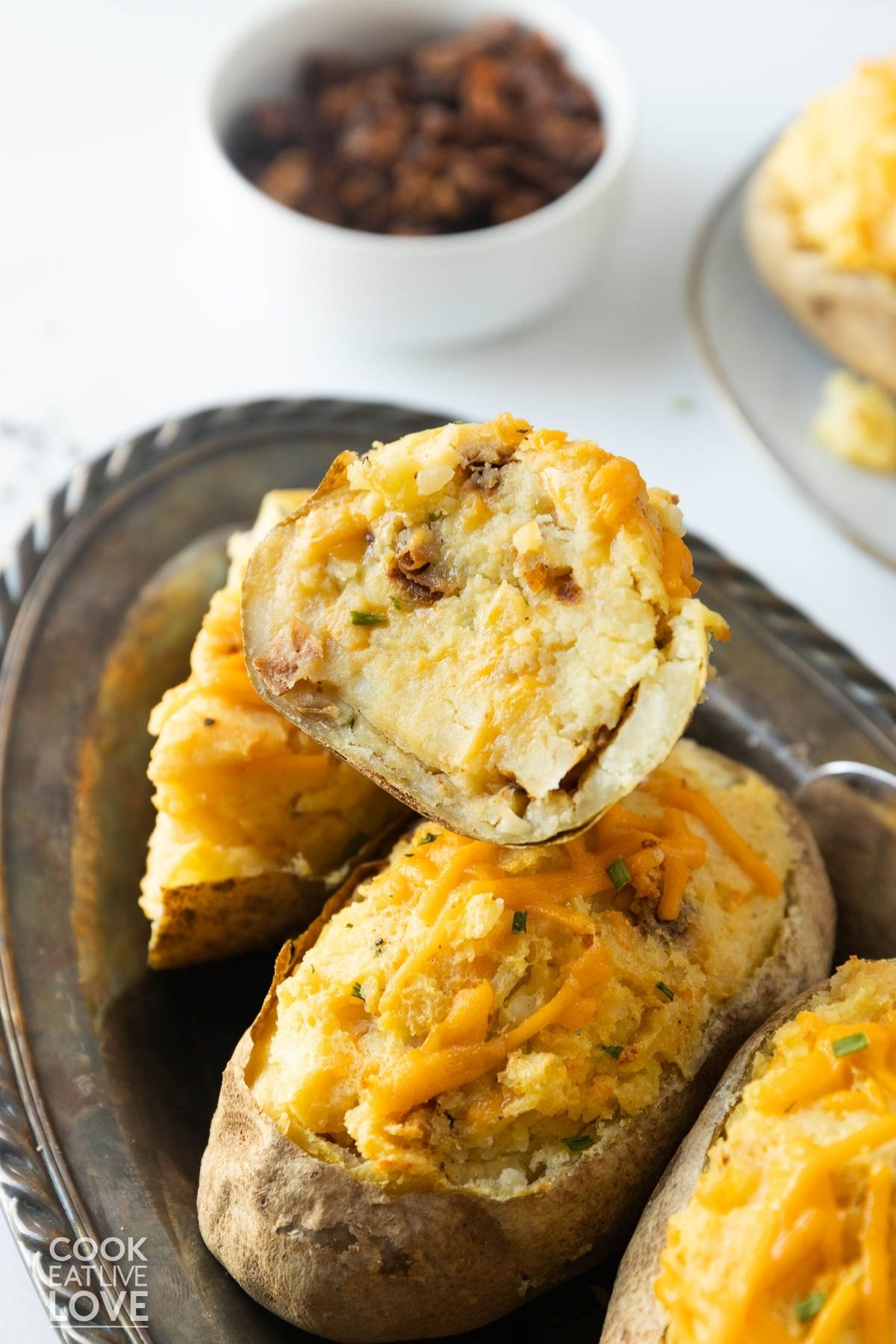 Vegan twice baked potatoes on a serving platter with one cut in half to show the inside. 