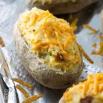 Vegan twice baked potatoes on a baking pan topped with melted cheese.