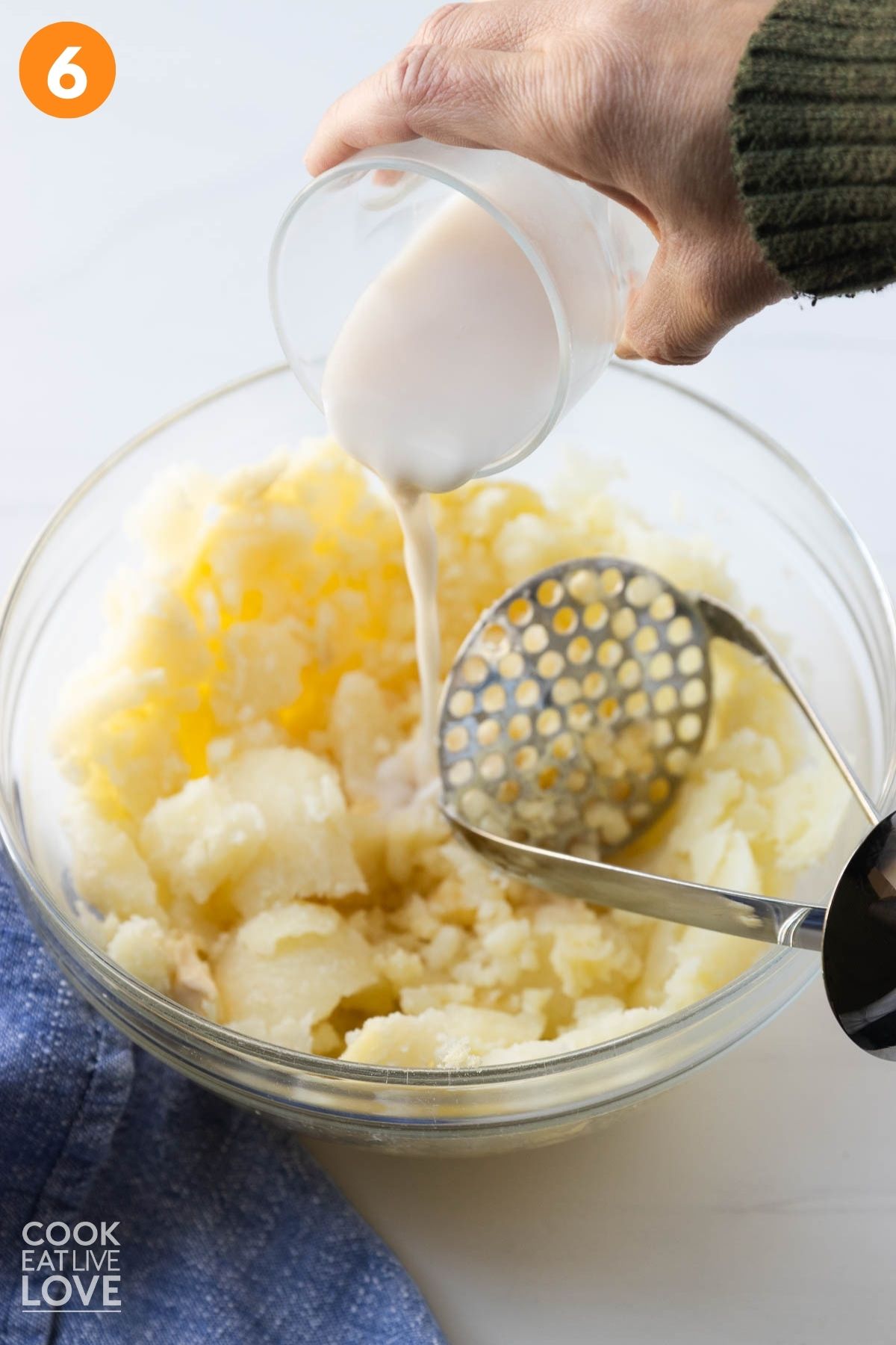 Adding milk and butter to the baked potato mixture. 