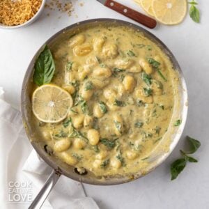 Creamy pesto gnocchi in a skillet.