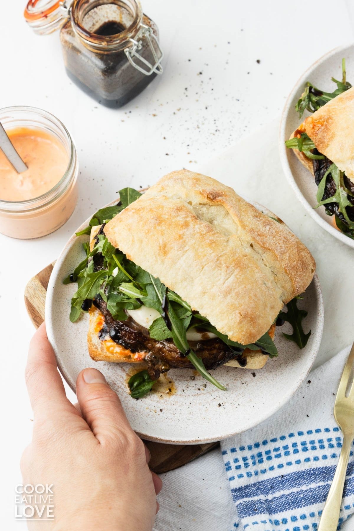 Portobello mushroom sandwich on a plate being picked up.