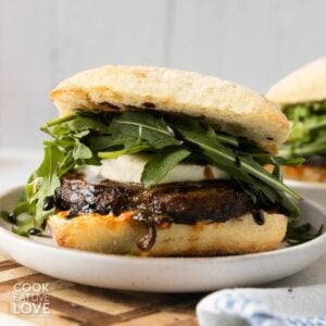 A sandwich with a portobello mushroom, mozzarella, and arugula.