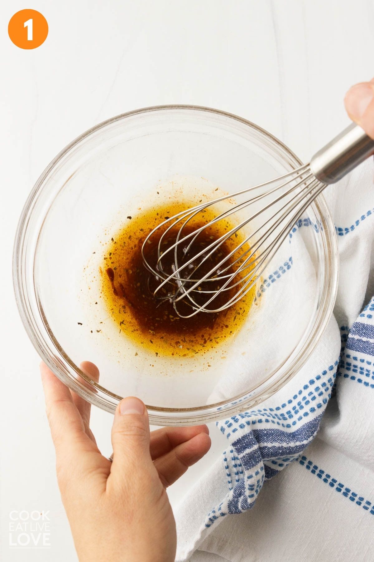Olive oil, balsamic vinegar, and seasonings combined in a bowl.