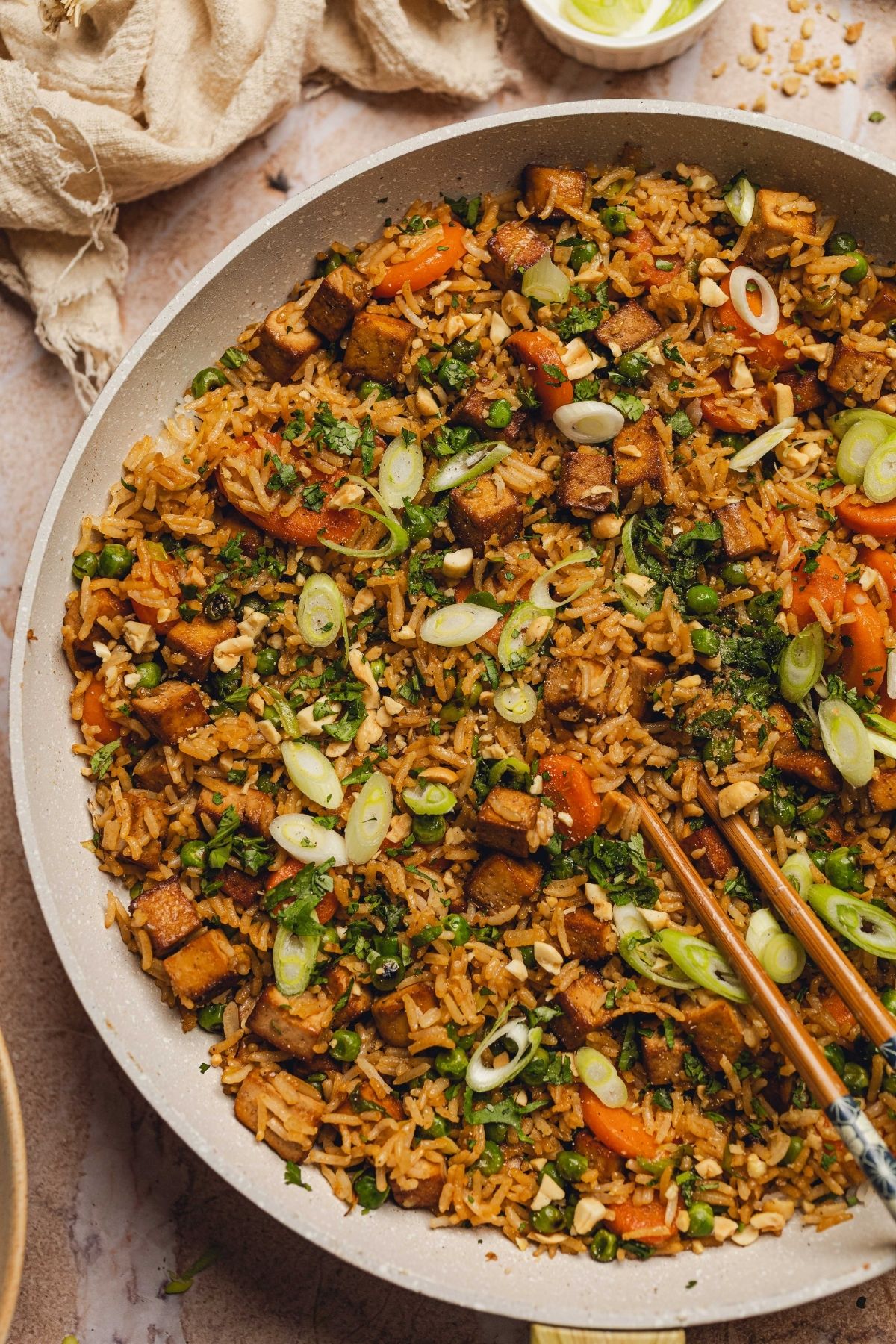 Chopsticks taking out some tofu fried rice from a skillet.