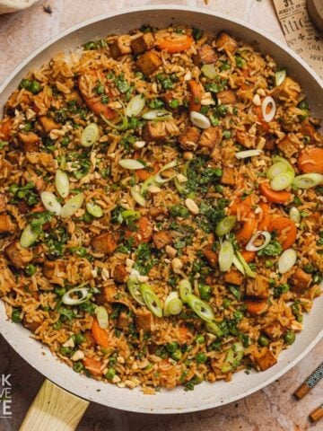 Tofu fried rice in a skillet garnished with green onions.