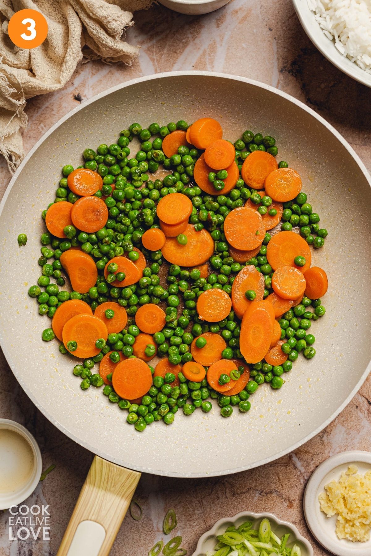 Pea and carrots in a skillet cooking.