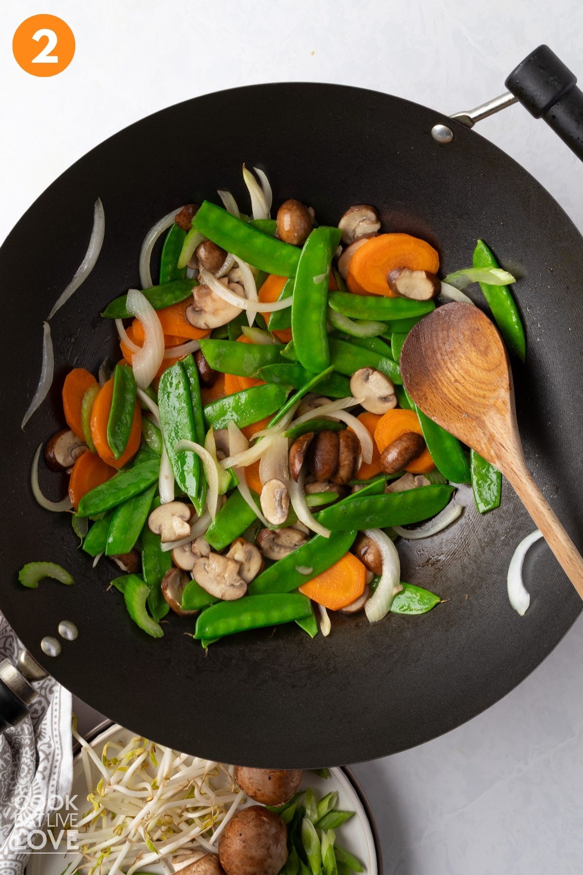 Carrots, snow peas, mushrooms, celery, and onions in a wok.
