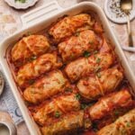 Pinterest graphic with image of stuffed vegetarian cabbage rolls in a casserole dish.