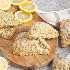 Lemon poppy seed scones stacked on top of one another on a wooden board.