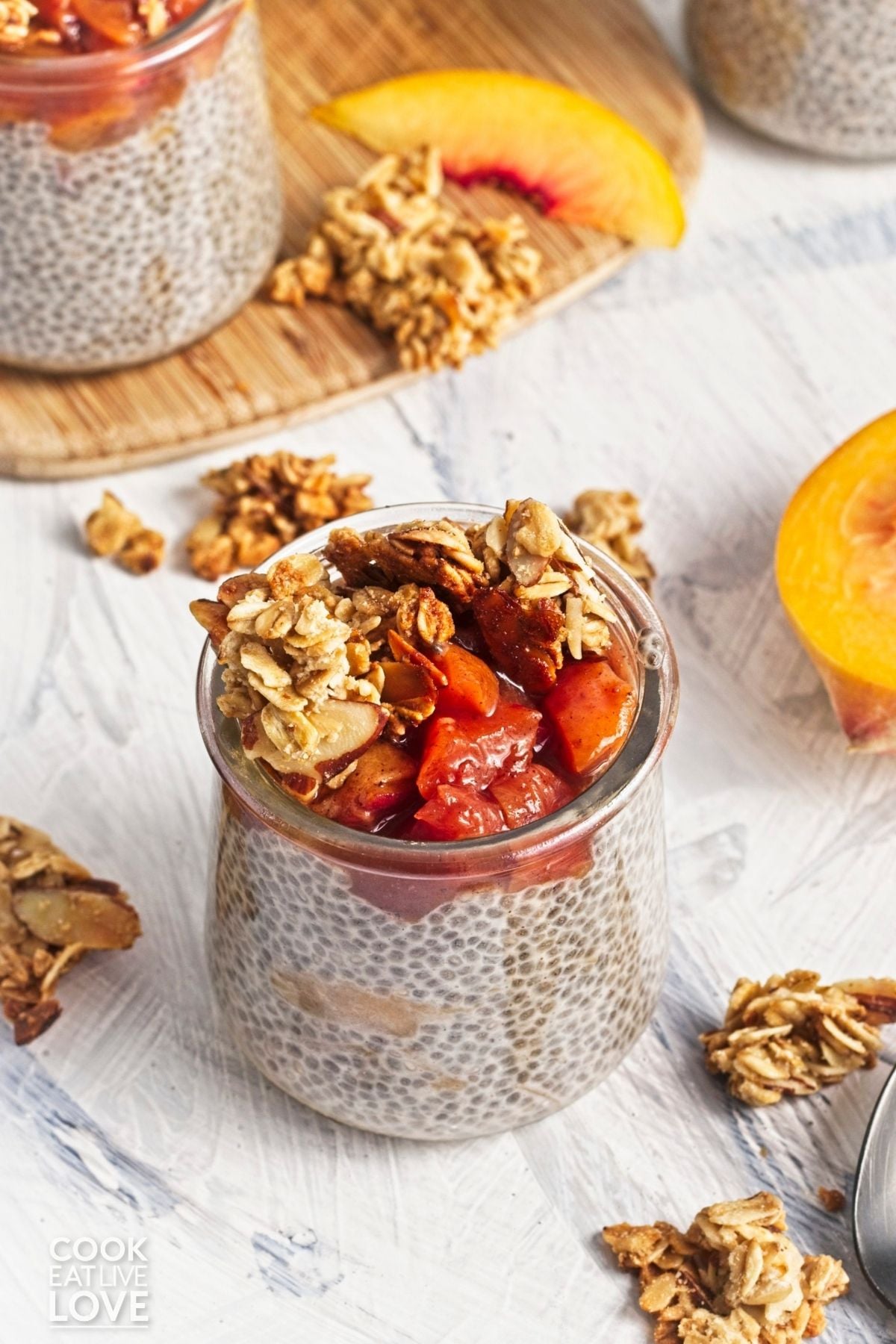 A jar filled with chia pudding with peaches and granola.