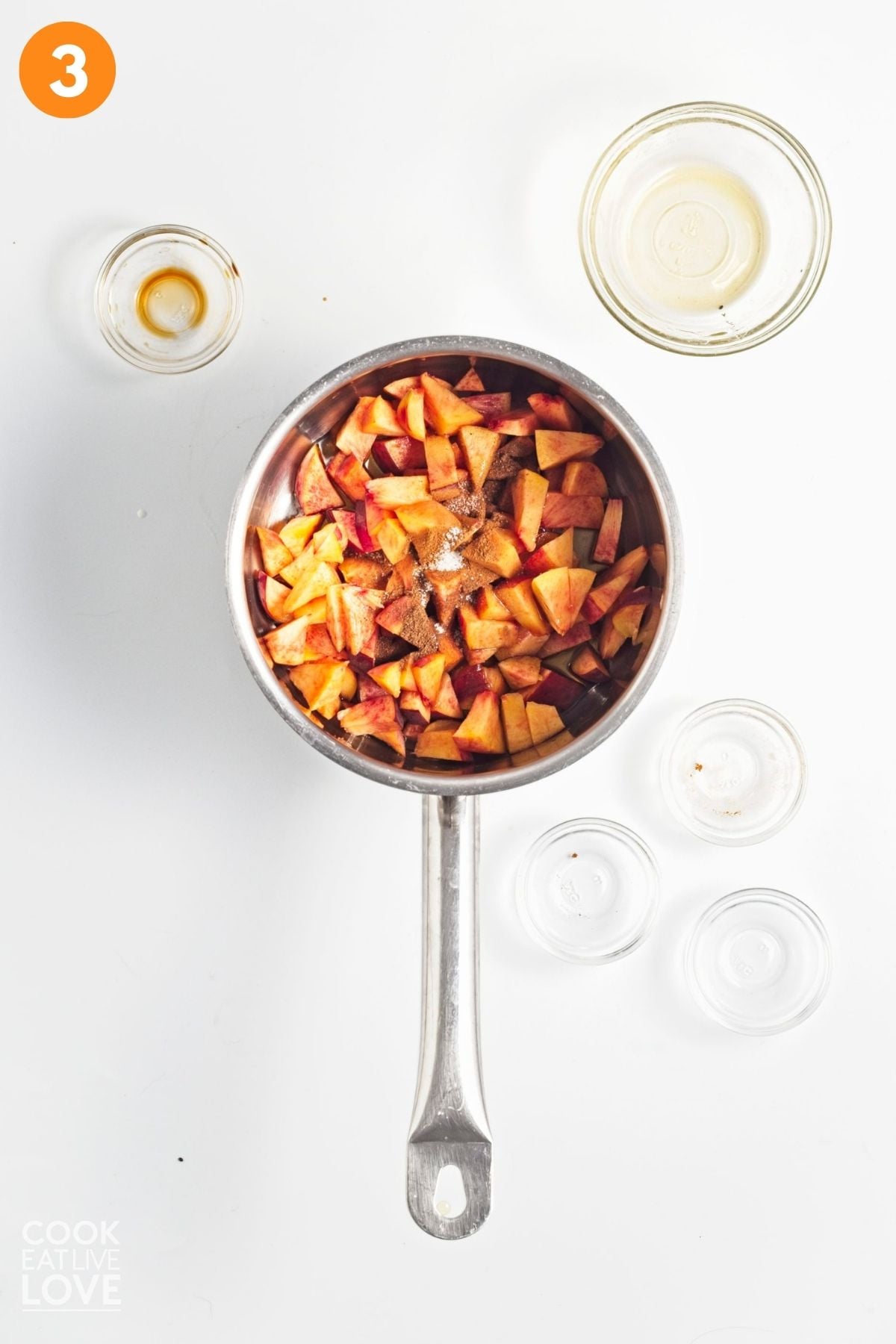 Peaches, maple syrup, vanilla, nutmeg, cinnamon, and salt heating in a saucepan.