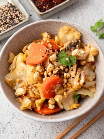 Tofu cabbage stir fry in a bowl with chopsticks on the side.