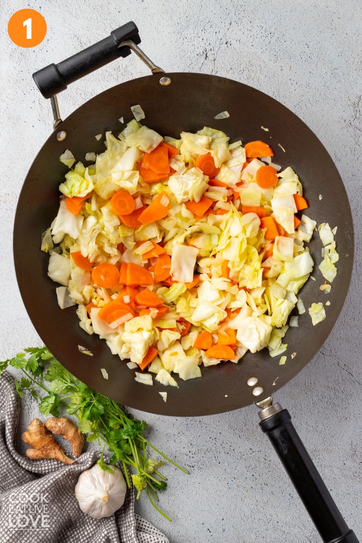Cabbage and carrots in a large wok.