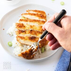A tofu katsu sliced up with a fork taking some.