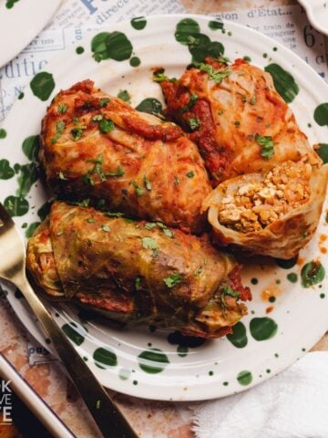 Cabbage rolls on a plate with one open.