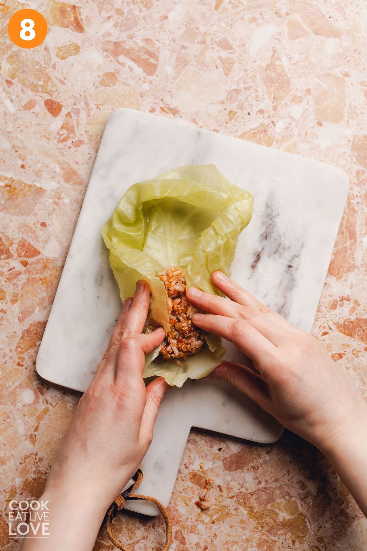 Hands rolling the cabbage leaf.